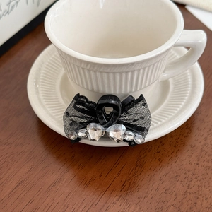 Barrette à cheveux élégante en dentelle noire avec strass brillants sur une tasse