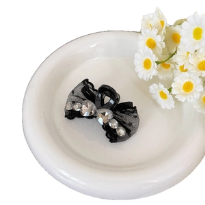 Pince à cheveux élégante en dentelle noire avec strass sur une assiette en céramique