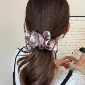 Pince à cheveux élégante en satin violet plissé avec strass brillants sur le modèle