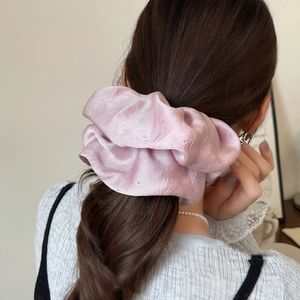 Pink satin scrunchie with sparkling rhinestones worn on a brunette ponytail