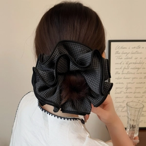 Macro detail of a gray plaid scrunchie with overlocked edges shown worn in a high bun