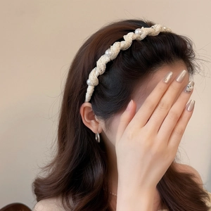 Elegant beige mesh pleated headband with white pearl accents on female model