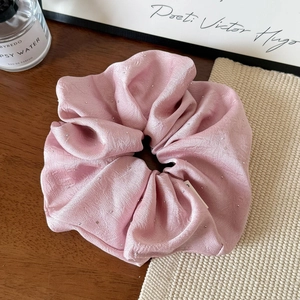 Detailed macro view of pink satin pleated hair scrunchie with sparkling rhinestones