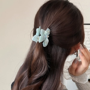 Gros plan d'une pince à cheveux papillon bleu menthe nacrée avec strass sur cheveux bruns