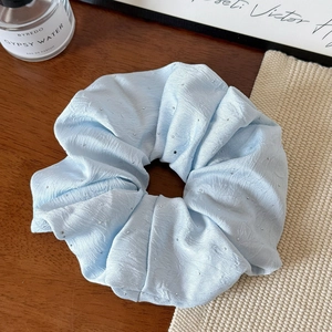 Detail view of light blue pleated scrunchie featuring elegant silver rhinestones on fabric