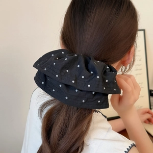 Schicker schwarzer Stoff-Scrunchie mit Punkten an einem braunen Pferdeschwanz