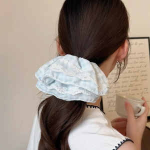 Chouchou à carreaux bleu clair avec dentelle porté sur une queue de cheval style d'été