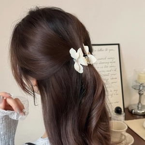 Détail d'une pince à cheveux fleur blanche avec pierre scintillante en demi-queue