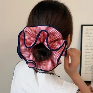 Large red and white plaid scrunchie with blue stitched edges on a woman's hair bun