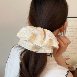 Chouchou à carreaux jaunes et bordure en dentelle sur cheveux, ambiance douce et élégante