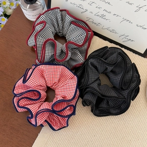 Detail of three plaid scrunchies with contrast edges on a vintage tabletop setting
