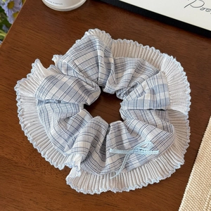 Détail du chouchou à carreaux bleus avec bordure plissée et petit nœud en ruban bleu