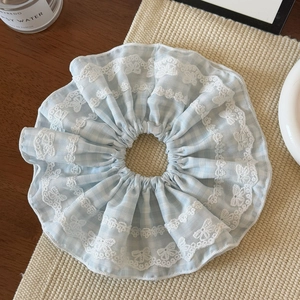 Gros plan d'un chouchou à carreaux bleus avec dentelle sur un fond esthétique chaud