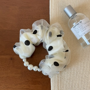Détail du chouchou en organza blanc à pois avec des accents élégants de perles nacrées