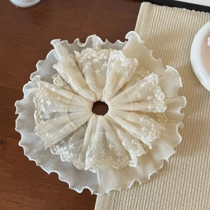 Close-up of oversized off-white lace hair scrunchie with delicate floral embroidery