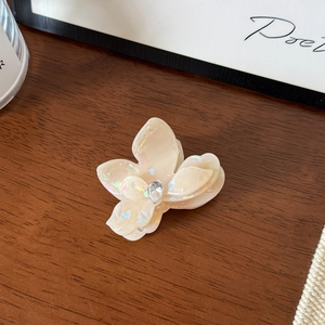 Détail d'une pince à cheveux fleur en acétate blanc crème avec cristal et fini nacré