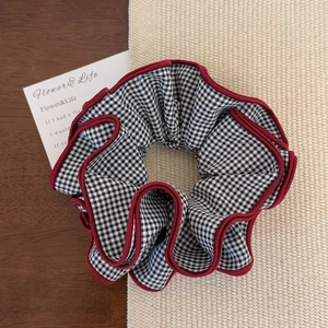 Detail of black and white gingham scrunchie with elegant red scalloped edge stitching
