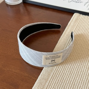 Détail d'un serre-tête en dentelle plissée gris clair avec doublure en velours noir