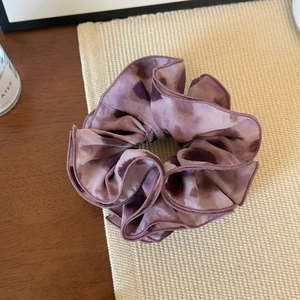 Macro shot of purple ink-wash patterned large silk hair scrunchie on woven mat