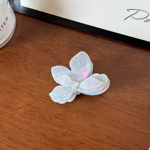 Gros plan sur pince à cheveux fleur en acétate avec strass sur table en bois