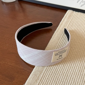 Vue détaillée d'un serre-tête large plissé en tissu lavande avec étiquette de style