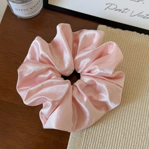 Detail eines rosa Satin-Haargummis mit seidiger Textur und glänzendem Perlmutt-Effekt
