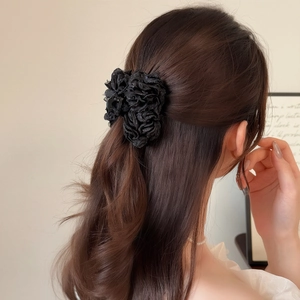 Pince à cheveux élégante avec pétales de tulle noir sur cheveux bruns ondulés