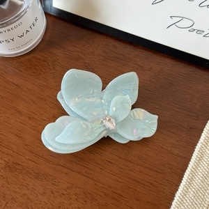 Détail d'une pince à cheveux fleurie bleue avec éclat nacré et cristal en forme de goutte