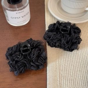 Détail de la pince à cheveux fleurie en organza noir multicouche sur une table