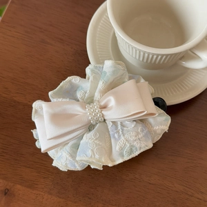 Detail of floral lace bow hair clip with pearls on a wooden aesthetic background