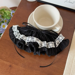 Detail of elegant black pleated lace hair clip with white floral embroidery and a bow
