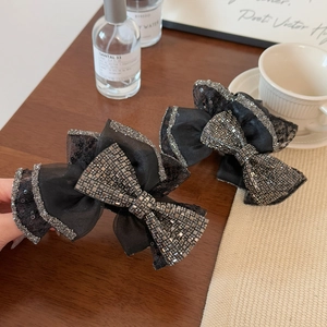Close-up of black mesh bow hair clips with sparkling square rhinestones and sequins