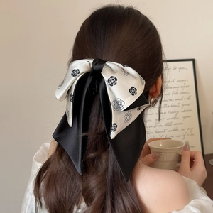 Elegant camellia bow hair claw clip for women featuring long black and white silk ribbons