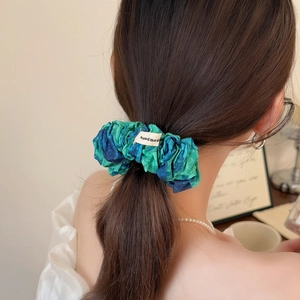 Chouchou plissé tie-dye bleu et vert avec étiquette fait main sur une coiffure queue de cheval