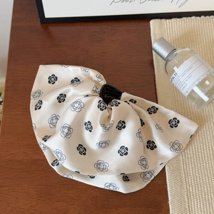 Détail d'une pince à cheveux en satin crème avec d'élégants motifs de camélia noir