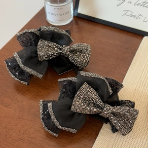 Elegant large black mesh bow hair claw with sequins and crystals on a wooden surface