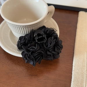 Détail d'une pince à cheveux à fleurs en maille noire multicouche sur bois rustique