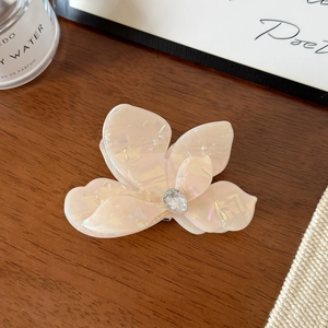 Gros plan d'une pince à cheveux fleur rose irisée avec strass sur un fond de bois