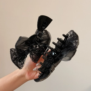 Detailed close-up of large black mesh bow hair claw clip with elegant sequined lace