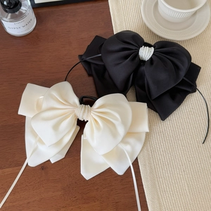 Elegant satin bow hair clip with pearl embellishments in black and cream colors