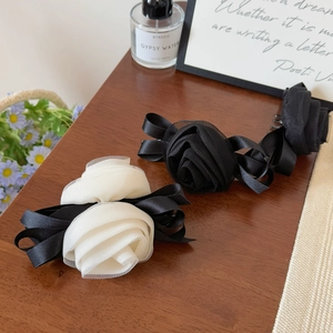 Detailed close-up of 3D mesh rose hair clips on a warm wooden table with accessories