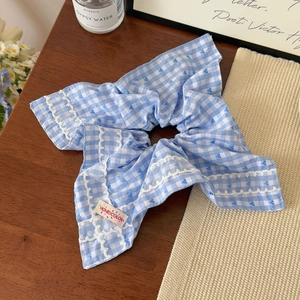 Détail d'un chouchou à carreaux bleus avec motifs de cœurs et bords en dentelle