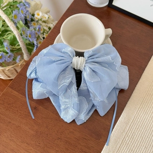 Gros plan d'une pince à cheveux à nœud brodé bleu clair avec perles sur table en bois