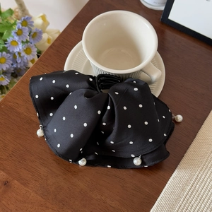 Vue détaillée d'une pince à cheveux en satin à pois avec perles élégantes