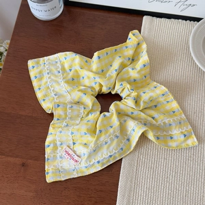 Vue détaillée du chouchou à carreaux jaunes avec cœurs bleus et bordure en dentelle