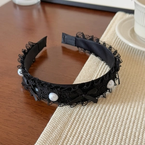 Détail d'un serre-tête en dentelle noire avec perles et petits nœuds élégants