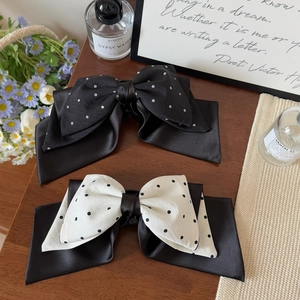 Chic retro polka dot satin bow hair clip set on a minimalist warm wood background
