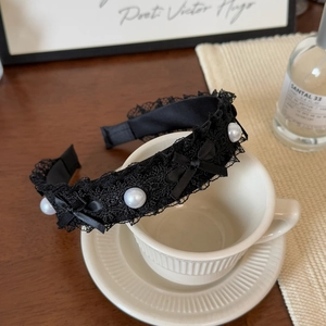 Détail d'un serre-tête en dentelle noire avec perles blanches et nœud en soie