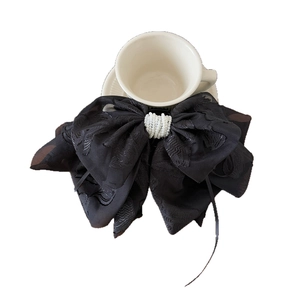 Barrette élégante en nœud brodé noir avec détail perle sur tasse blanche