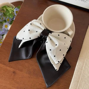 Close-up of French vintage black and white polka dot satin bow hair clip on wooden desk